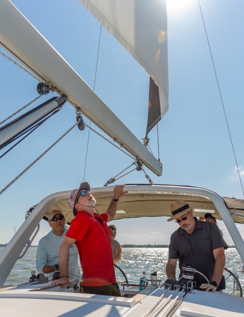 Skeleton Crew Adventures instructor guiding veterans as they raise the mainsail during an October daysail, demonstrating teamwork and hands-on sailing experience.